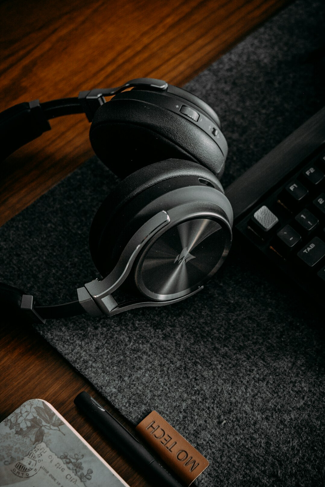 Close-up of hands editing audio waveforms on a laptop with headphones nearby